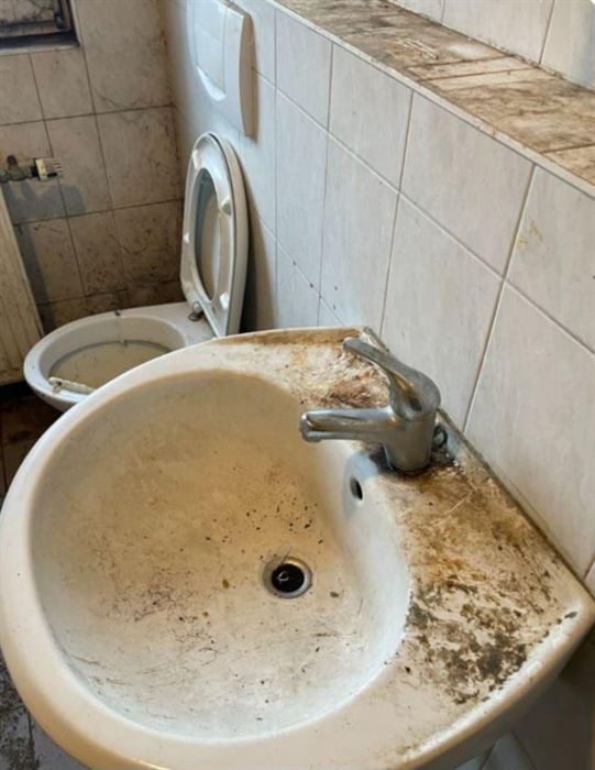 Waschbecken vor der Reinigung: dicke Kalk- und Schmutzschicht auf Becken, Armatur und Ablage