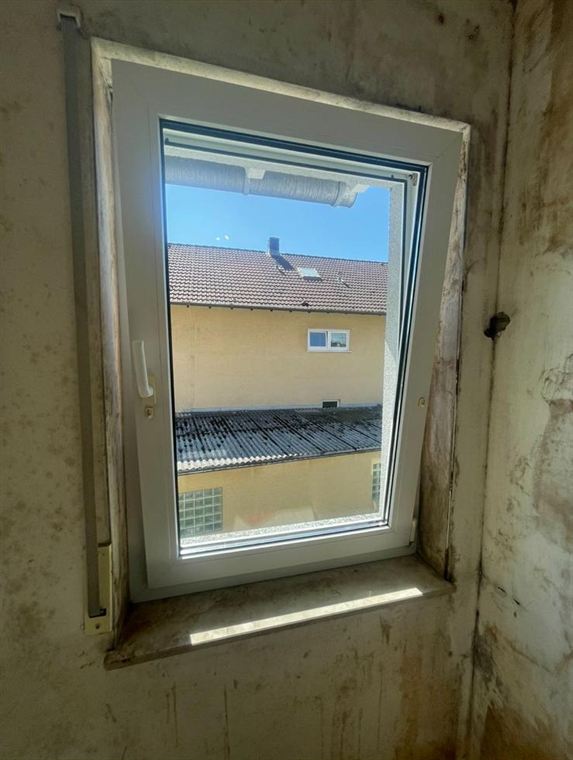 Gereinigtes Fenster in einem unsanierten Raum mit roher Wand