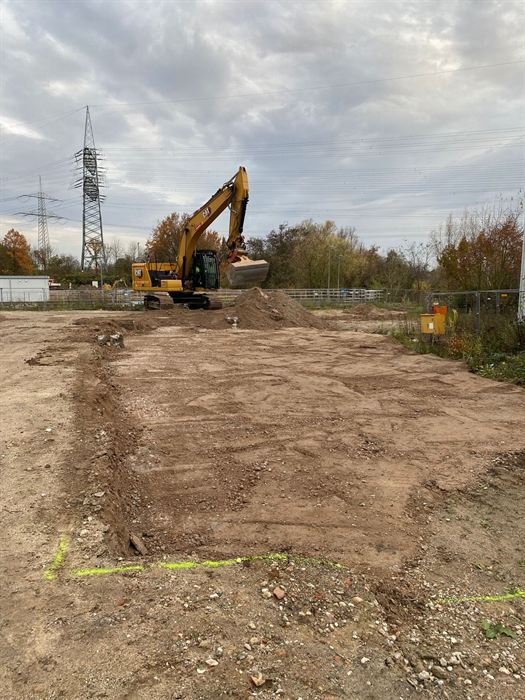 Geräumte Baustelle mit Kettenbagger und freigelegten Fundamentgräben