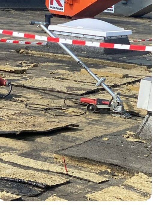 Abgesperrter Dachbereich mit orangefarbenem Container und abgetragener Dämmung
